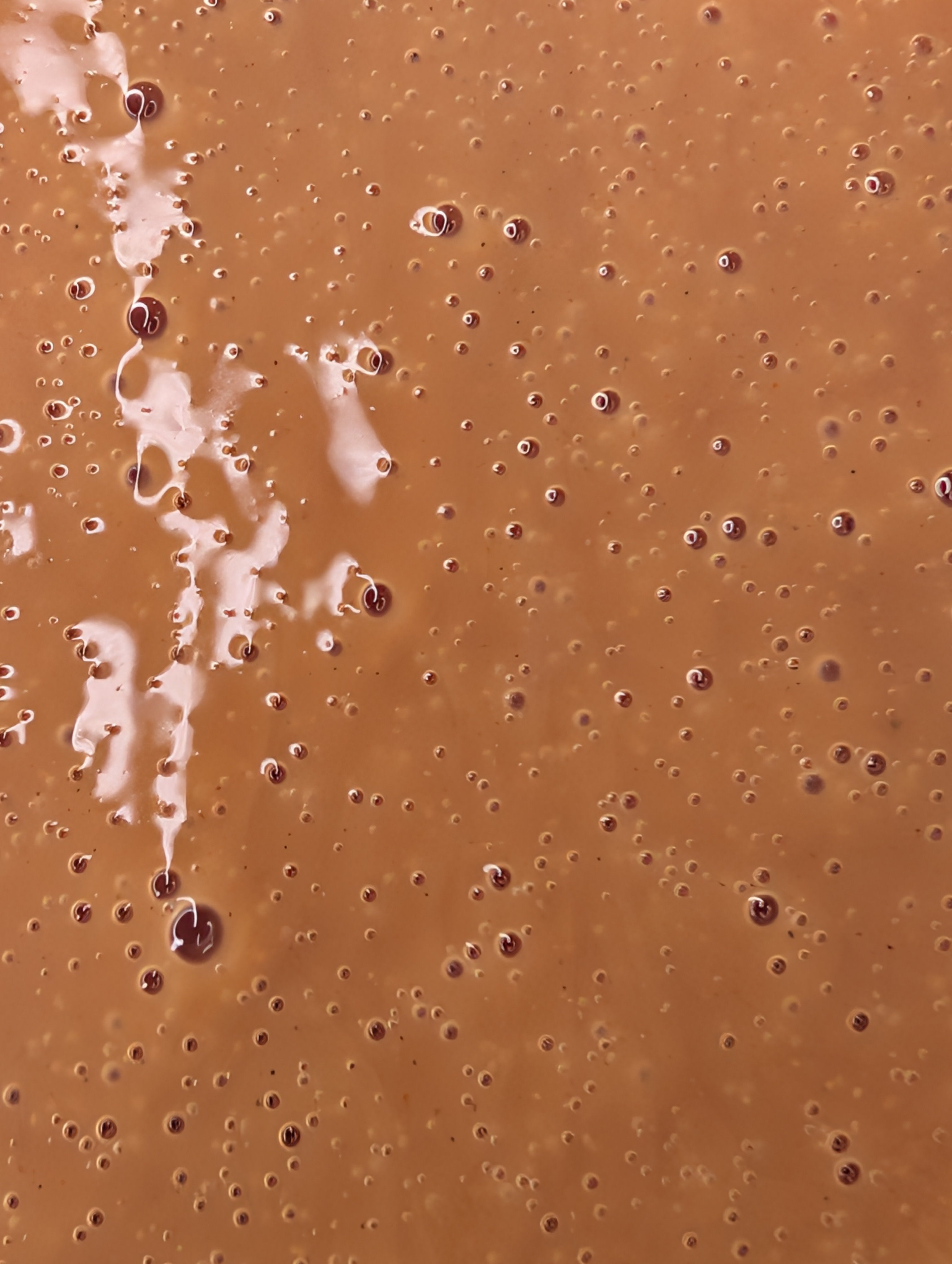 Close-up of a mocha-colored face cleanser with bubbles and suds